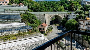 Una zona residencial en una ladera con un puente de piedra, una carretera y un invernadero con paneles solares.