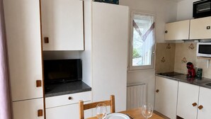 Eine kompakte Küche mit Esstisch, Stühlen, einem Fernseher und einer Mikrowelle.