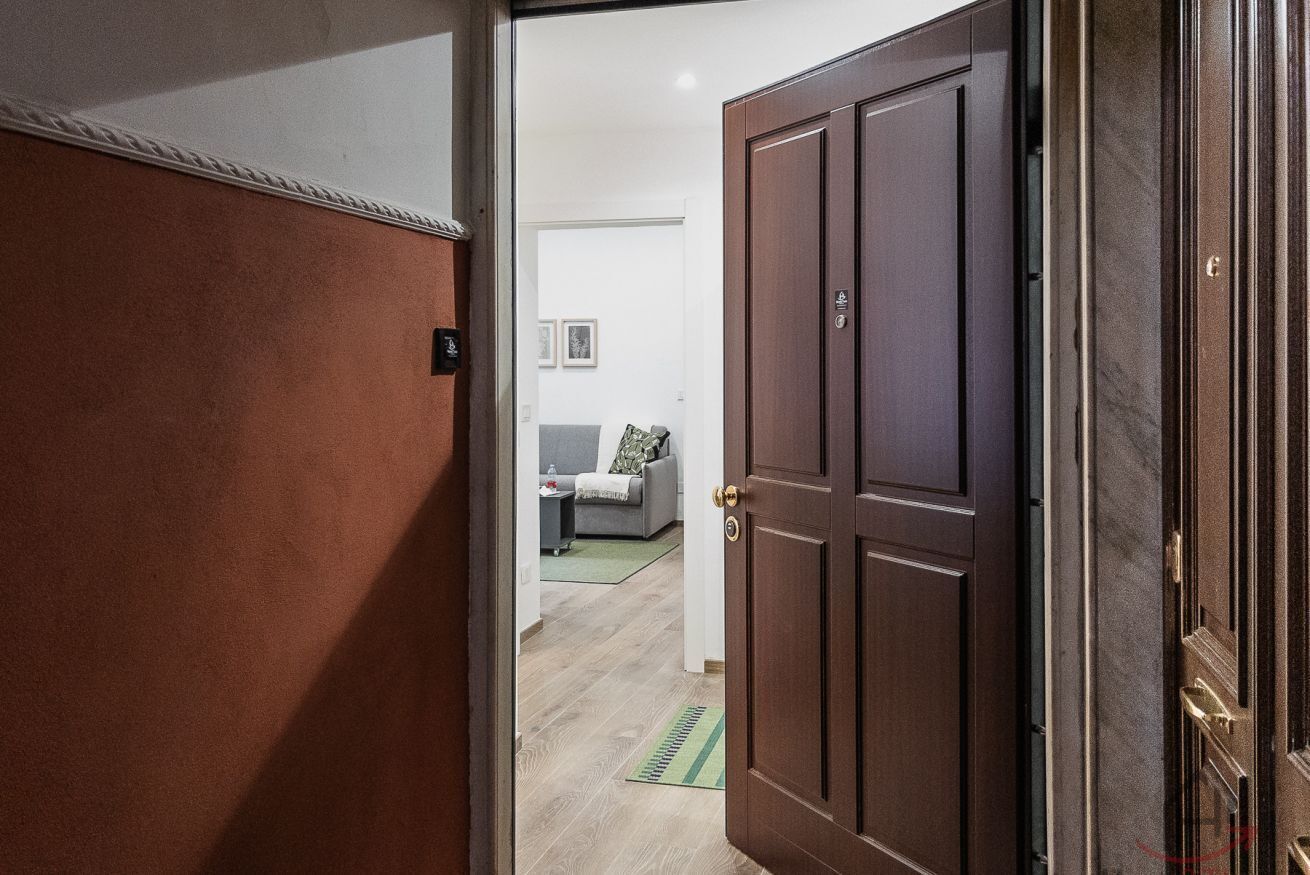 Une porte qui donne sur un espace de vie comprenant un canapé, une petite table et un tapis.