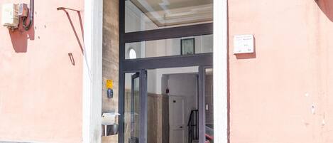 A building entrance with a glass door, a staircase, and a wall-mounted sign.