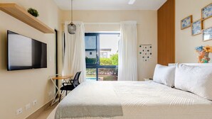 Hotellihuone, jossa on sänky, televisio, työpöytä ja näkymä ulos.