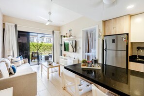 Een moderne keuken met een zwart aanrecht, roestvrijstalen apparatuur en een zithoek met een bank en tafel.