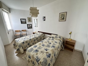 A bedroom with two beds, a desk, a chair, and a shelf. - Comfortable Stay in a Great Area (San Michele al Tagliamento)