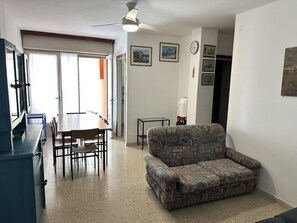 A living room with a sofa, a dining table with chairs, a ceiling fan, and a clock on the wall. - Comfortable Stay in a Great Area (San Michele al Tagliamento)