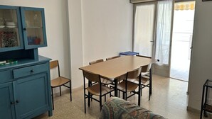 A dining area with a table and chairs, a blue cabinet with glass doors, and a view through a window with curtains. - Comfortable Stay in a Great Area (San Michele al Tagliamento)