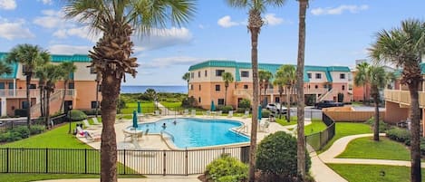 Un resort con piscina, palme e vista sull'oceano.