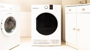 A laundry room with a front-loading washer and dryer, a cabinet with drawers, and a pink rug on the floor. - CENTRAL 55m2 - 4 PERSONNES - COSY - PROCHE NAUSICAA (Boulogne-sur-Mer)