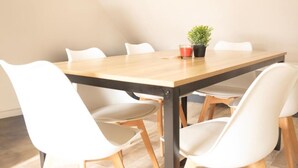 A dining table with six white chairs, a potted plant, and a glass of red drink. - CENTRAL 55m2 - 4 PERSONNES - COSY - PROCHE NAUSICAA (Boulogne-sur-Mer)