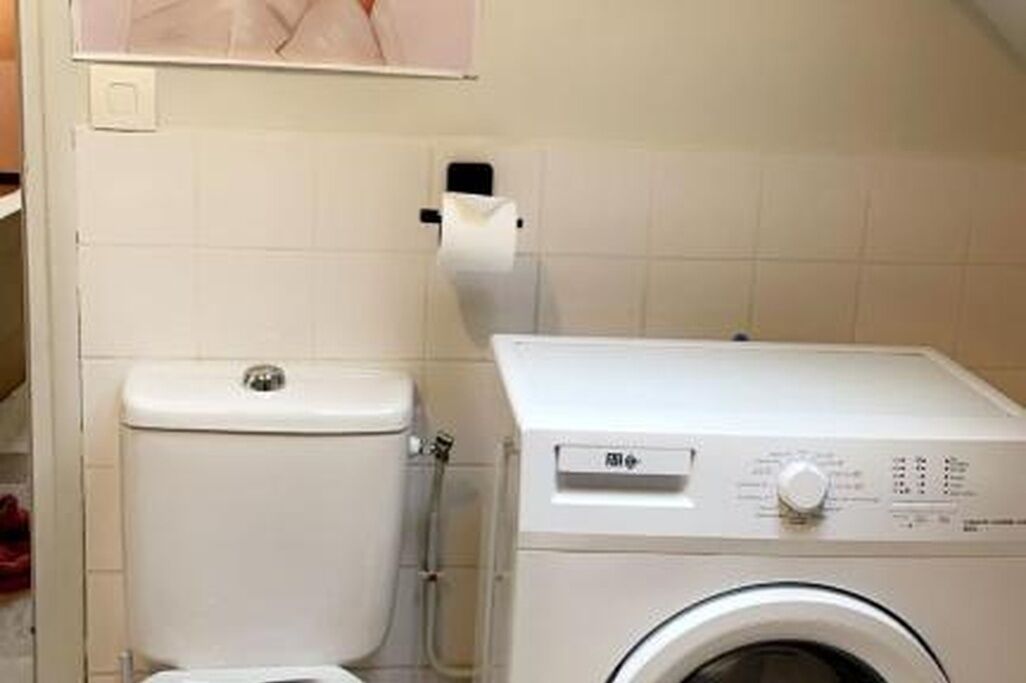 Un baño pequeño con inodoro, lavadora y dispensador de toallas de papel.