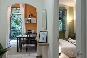 Una habitación moderna con una cama, un comedor con sillas, una mesita y una ventana con cortinas.