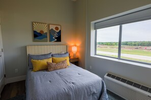 A bedroom with a bed, a nightstand, a lamp, and a window with a view of a landscape. - Airplane/Hanger Apartment 2 bedrooms 2bathrooms #4 (Salado)