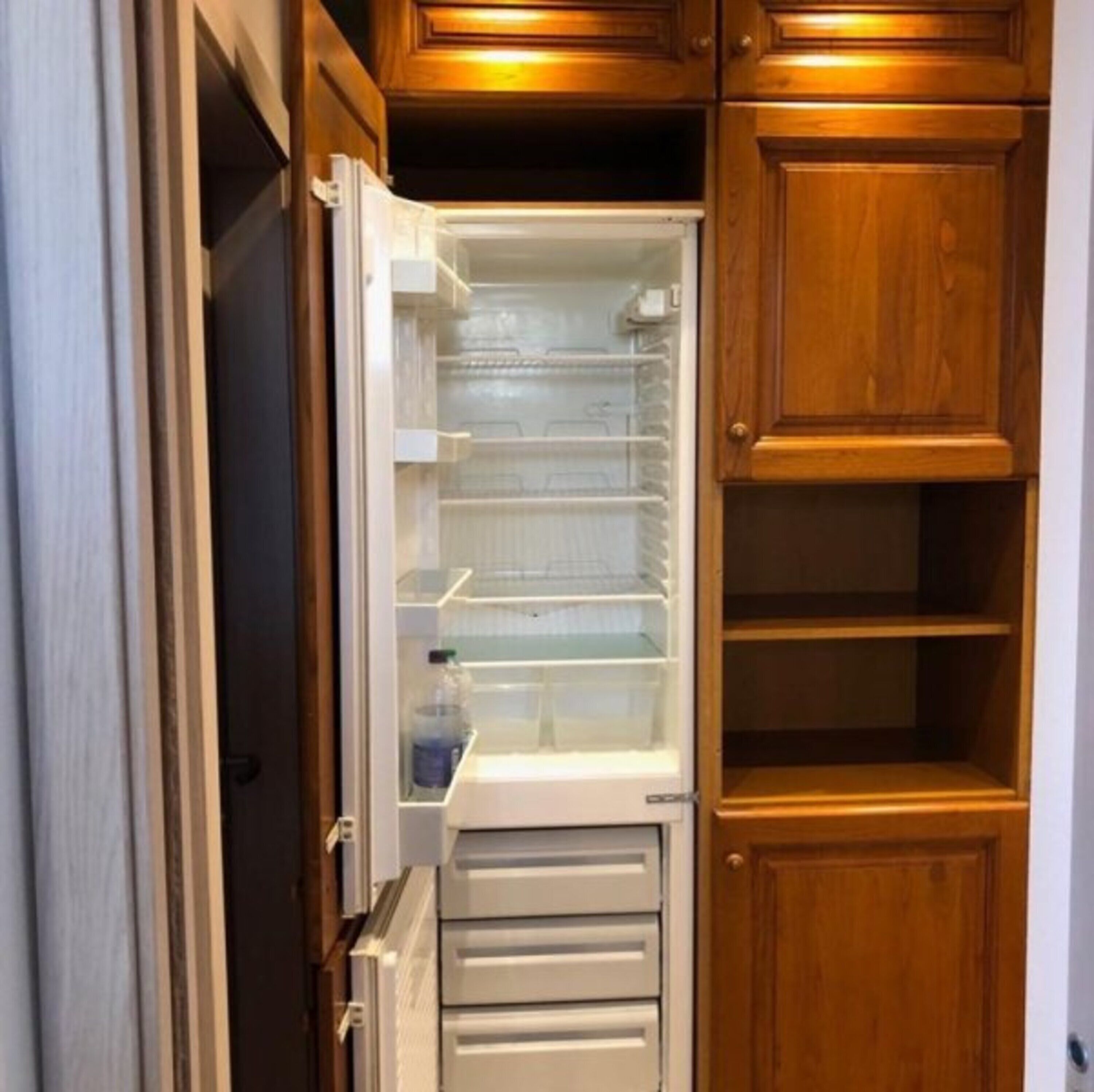 A compact kitchen with wooden cabinets and a built-in refrigerator.