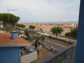 A balcony with a view of a beach, a street, and a building with a red roof. - Seafront Flat With Splendid Views From the Terrace (San Michele al Tagliamento)