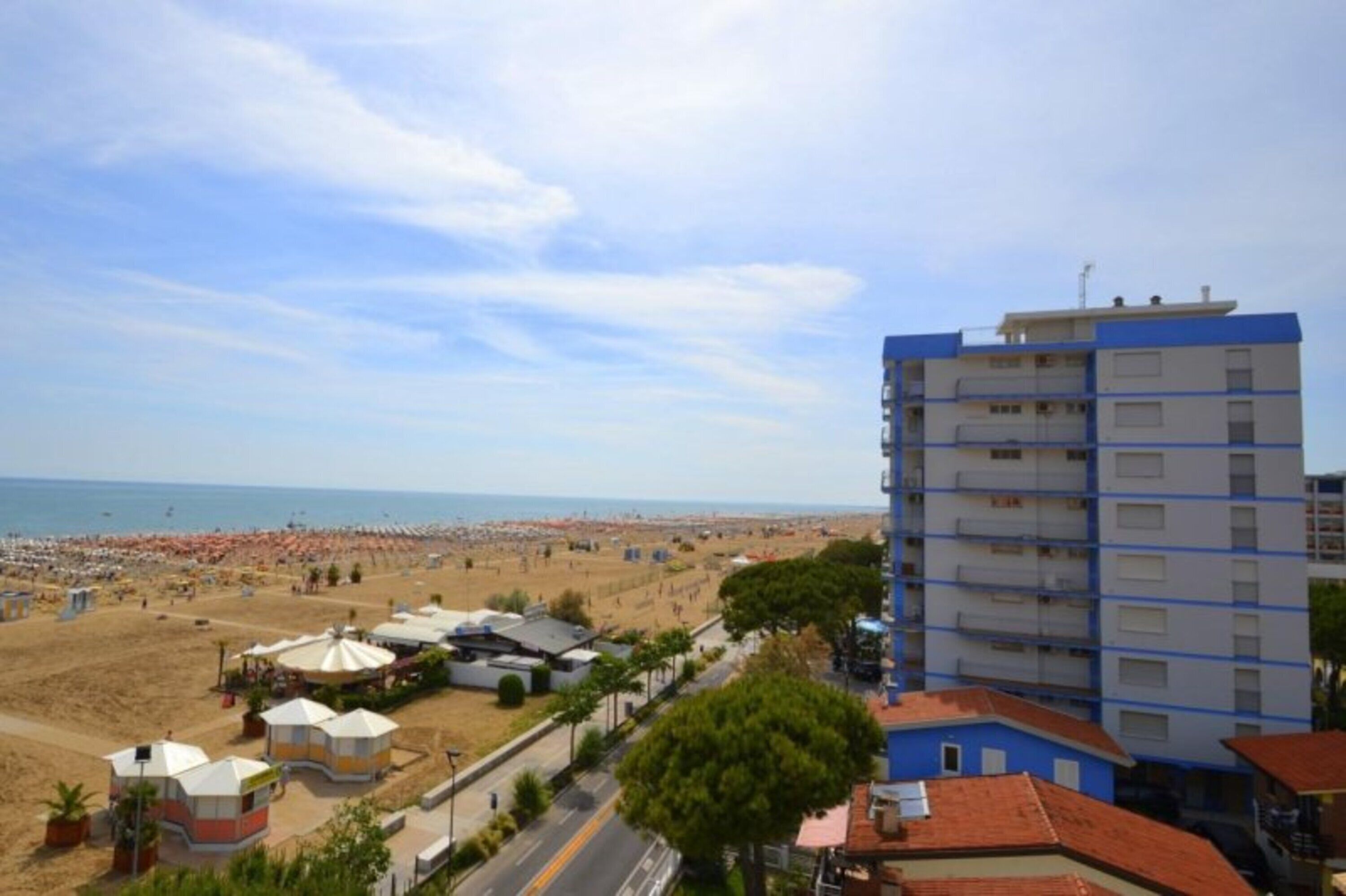A coastal view with a beach, a blue and white building, and a clear sky.