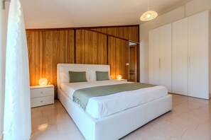 A bedroom with a bed, nightstands, a wardrobe, and a wooden panel wall.