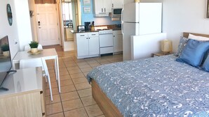 Ein kleines Zimmer mit Bett, Schreibtisch und Küchenzeile.