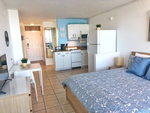 Ein Schlafzimmer mit Bett, Schreibtisch, Stuhl, einer Küchenzeile und einem Badezimmer.