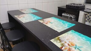 Een keuken met witte betegelde wanden, een zwart aanrecht en een gasfornuis.