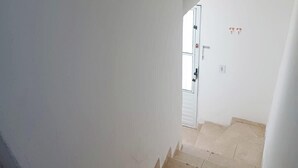 Een trap met beige tegels die leidt naar een deur met een witte omlijsting en een klein raam.