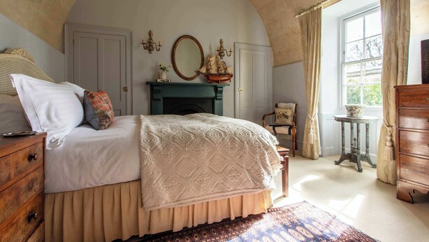 Une chambre à coucher comprenant un lit, une commode, une coiffeuse et une fenêtre avec des rideaux.