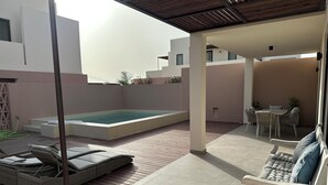 A modern outdoor patio with a swimming pool, lounge chairs, and a dining area.
