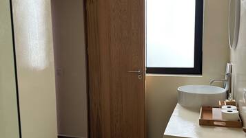 A bathroom with a bidet, toilet, sink, and a wooden door.
