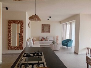Une cuisine moderne avec un îlot central, un coin repas comprenant une table, un canapé et un fauteuil bleu.