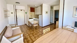 Ein kompakter Wohnraum mit Essbereich, Küchenzeile und einem separaten Zimmer mit Bett.