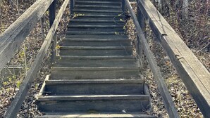 A wooden staircase with metal railings leading up to a bridge. - Escape to Lake Metigoshe This Summer (Bottineau)