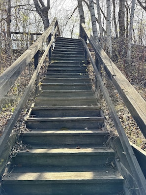 Eine Holztreppe mit Metallgeländern, die zu einer Brücke führt.