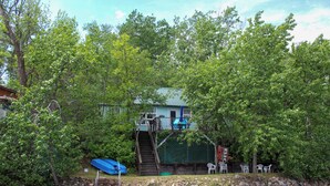 A dock leading to a house surrounded by trees. - Escape to Lake Metigoshe This Summer (Bottineau)