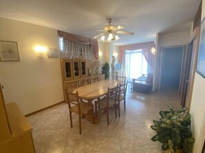 Ein Essbereich mit Holztisch und Stühlen, einem Deckenventilator und einem Blumentopf.