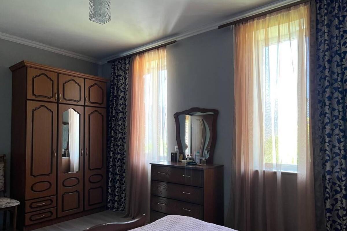 Un dormitorio con cama, armario, cómoda y espejo.