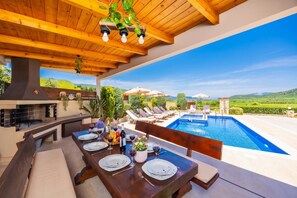 An outdoor dining area with a pool, wooden ceiling, and a view of the countryside. - Villa Maggie Alonia - Four Bedroom Villa, Sleeps 8 (Zakinthos)