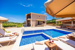 Un espace piscine comprenant des chaises longues, une petite piscine et un bâtiment doté d’un balcon.
