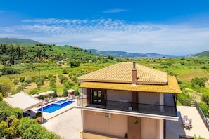 Ein zweistöckiges Gebäude mit Schwimmbad, Balkon und Blick auf eine grüne Landschaft.