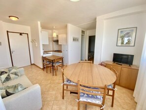 A compact living space with a dining area, kitchenette, and a television. - Modern Beachfront Stay With Parking (San Michele al Tagliamento)