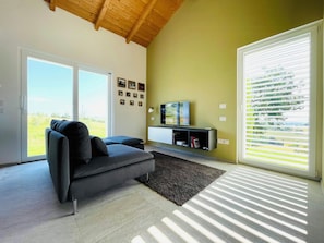 A modern living room with a sofa, TV, and large windows. - Wellness hillside house in Le Marche (Recanati)