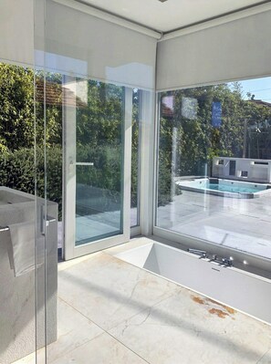 Ein modernes Interieur mit großen Glasüren, die zu einem Außenbereich mit Pool und einer Terrasse mit Grill führen.