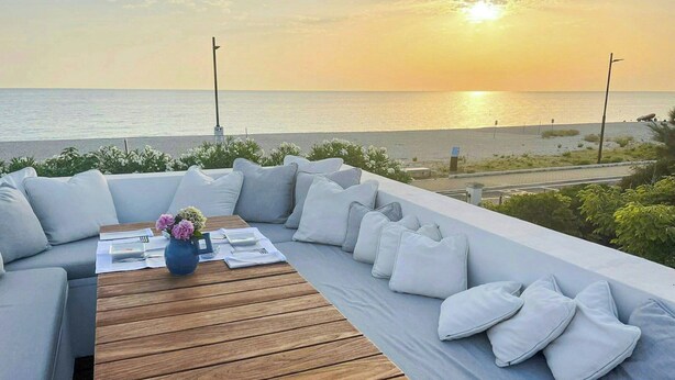 A seaside terrace with a wooden table, white cushions, and a vase of flowers. - Beachfront villa with jacuzzi in Senigallia (Marzocca)