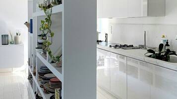 Une cuisine moderne avec des meubles blancs, un îlot central et une grande fenêtre.