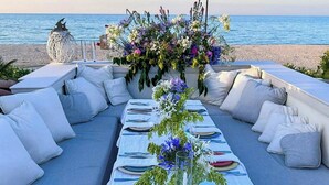 An outdoor dining area with a view of the sea, a long table set with plates and glasses, and a decorative centerpiece. - Beachfront villa with jacuzzi in Senigallia (Marzocca)