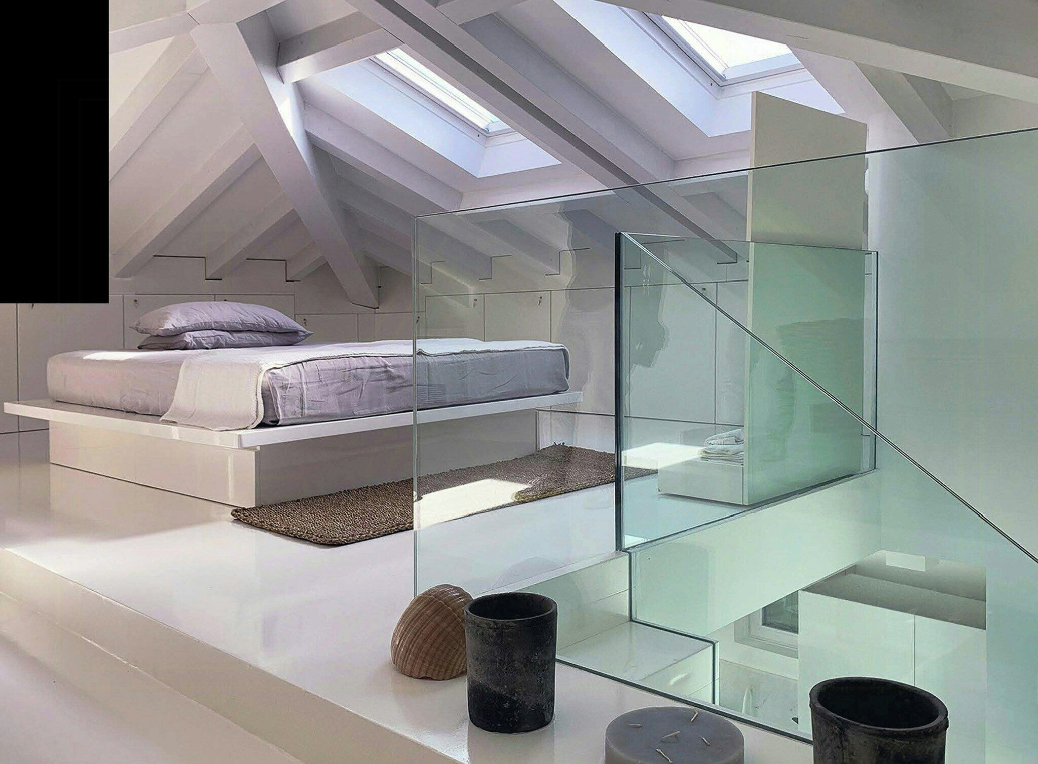 Une chambre moderne dotée d’une lucarne, de murs en verre et d’un lit offrant une vue imprenable.