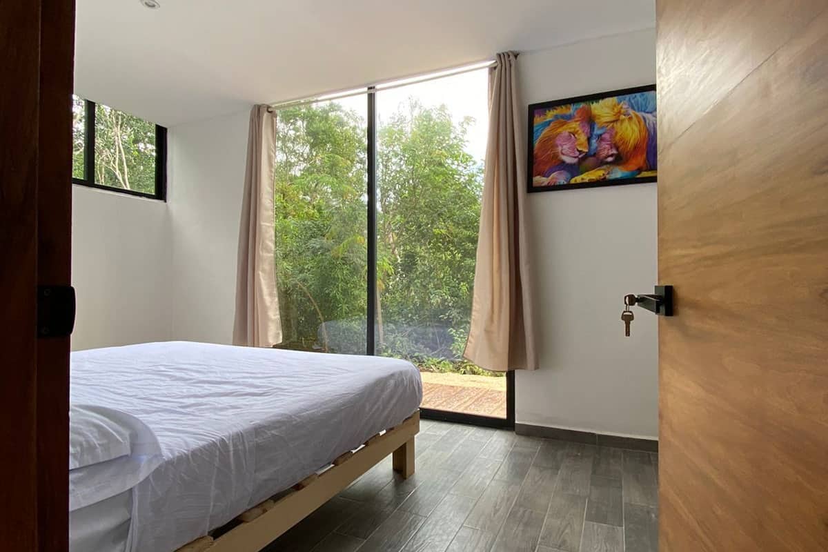 A bedroom with a bed, a window, and a door.