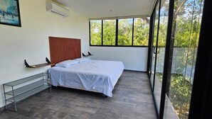 Un dormitorio con cama, ventana, un cuadro y balcón.