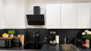 A modern kitchen with a black countertop, stainless steel appliances, and white cabinetry. - Velmora Boutique Suites: 2 e-bikes included (Lübeck)