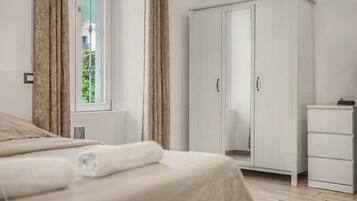 A bedroom with a bed, a wardrobe, a bedside table, and a window with curtains.
