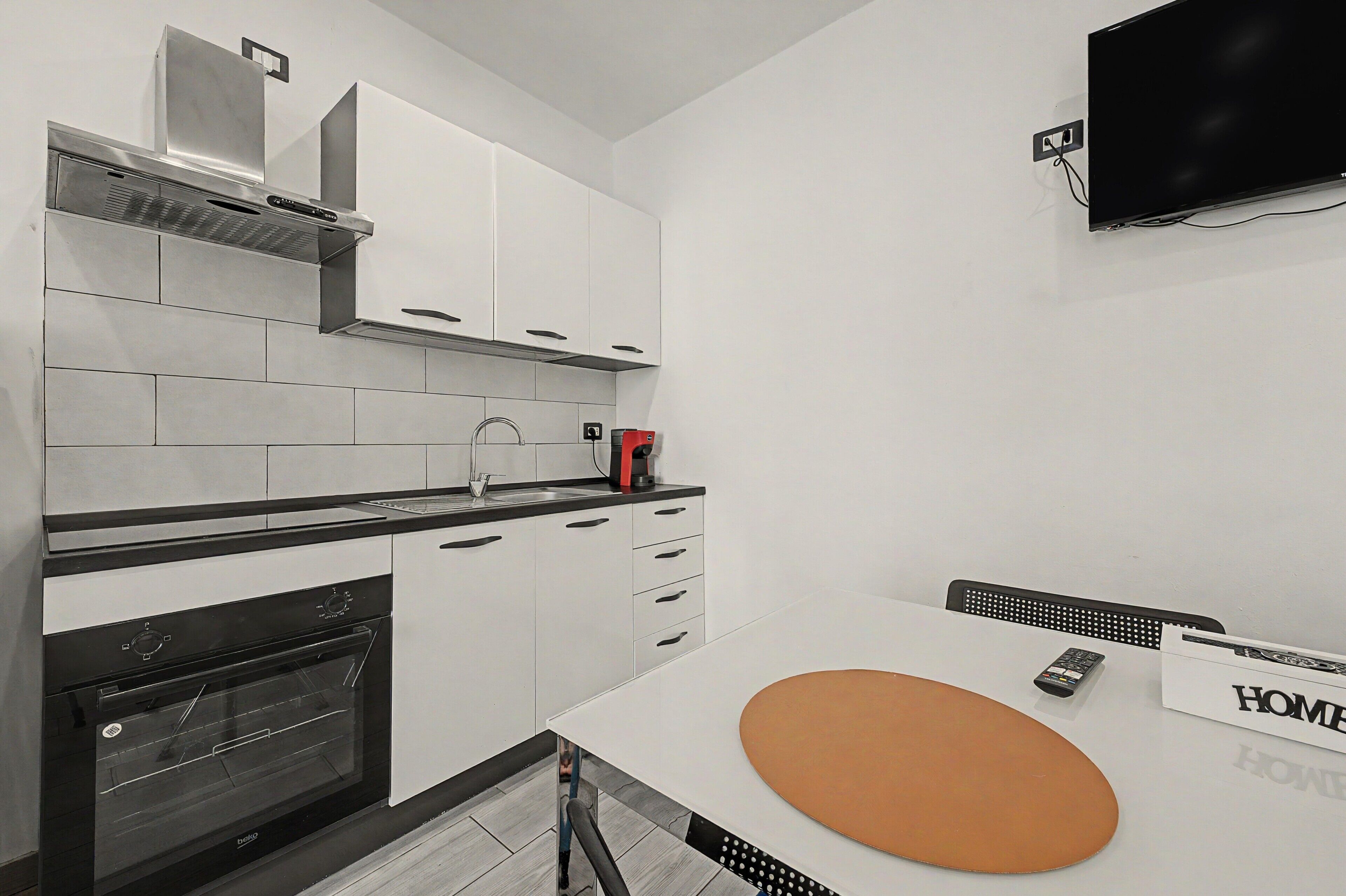 Eine moderne Küche mit weißen Schränken, einer schwarzen Arbeitsplatte und einem eingebauten Backofen.