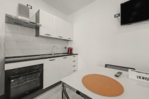 A modern kitchen with white cabinetry, a black countertop, and a built-in oven.