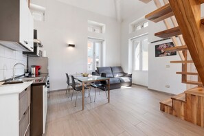 A modern kitchen with a dining area, a sofa, and a wooden staircase. - Apartment 'Gold' with Wi-Fi and Air Conditioning (Delebio)